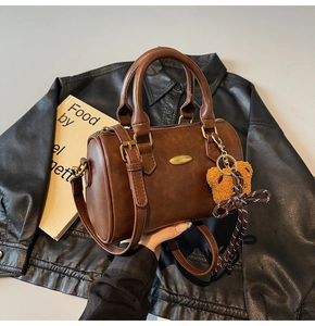 Close-up of retro brown Boston bag on leather jacket with a cute teddy bear charm