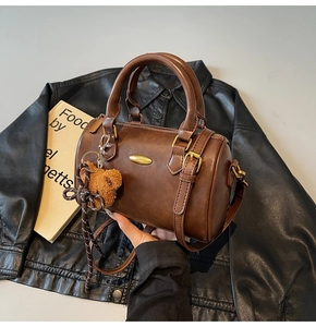 Detailed view of a brown vintage Boston bag with a cute bear charm and golden hardware