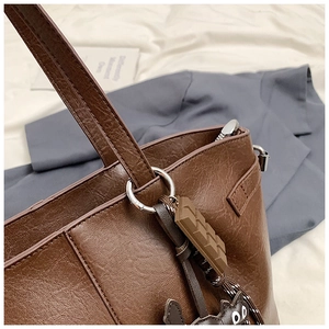 Detail einer braunen Vintage-Tasche mit Silberbeschlägen und Schokoladen-Katzenanhängern