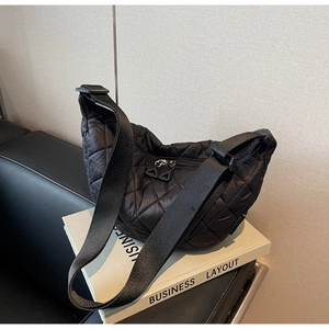 Détail du sac bandoulière en nylon matelassé noir avec sangle large et zips triangulaires