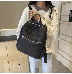 Close-up of black quilted puffer backpack with soft texture and silver zippers
