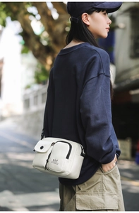 Outdoor shot of the minimalist beige crossbody bag shown on a model in the street