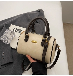 Detail of cream Boston bag with dark brown trim and adjustable crossbody shoulder strap