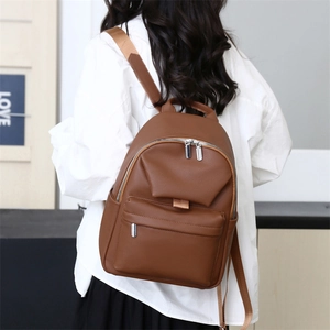 Rear view of model wearing a brown lychee pattern PU leather backpack with silver zippers