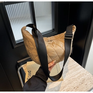 Détail du sac croissant en nylon matelassé beige avec large bandoulière noire