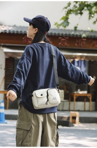 Close-up of cream multi-pocket crossbody bag with black strap and tactical design