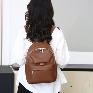 Detail of dark brown pebbled leather texture and silver zippers on women backpack