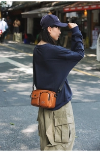 Close-up of brown leather crossbody bag featuring unique double front pockets and adjustable strap