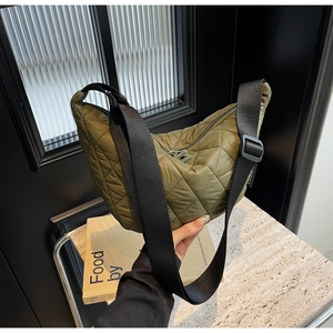 Détail du sac bandoulière en nylon matelassé vert olive avec large sangle noire réglable