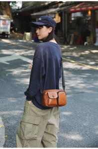 Close-up of brown leather crossbody bag with multiple pockets and adjustable shoulder strap