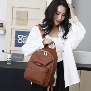 Detail view of the brown pebble leather texture and metallic zippers on the stylish backpack