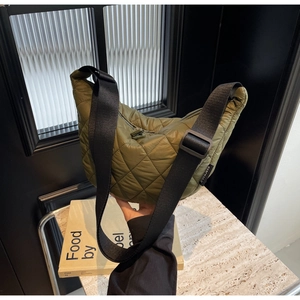 Détail du sac demi-lune matelassé vert olive avec une large bandoulière noire réglable