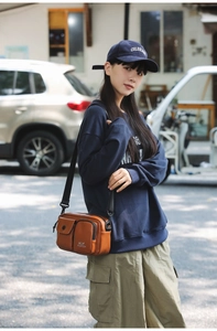Detailed view of a brown leather phone bag with multi-pockets and adjustable strap
