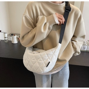 Sac demi-lune en nylon blanc matelassé porté par un mannequin dans un café