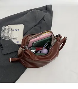 Vue intérieure d'un grand cabas en cuir marron avec tablette et accessoires quotidiens
