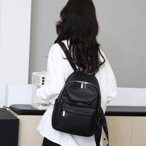 Rear view of model wearing black litchi leather backpack with double zippers