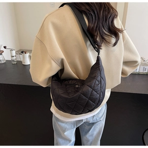 Vue détaillée d'un sac demi-lune en nylon matelassé noir porté en bandoulière