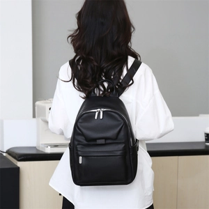 Classic black leather backpack shown on a model in a minimalist white shirt setting