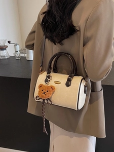Boston style cream suede handbag with brown handles and cute bear charm shown on model
