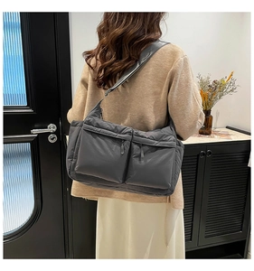 Détail du sac bandoulière en nylon matelassé gris foncé avec deux poches zippées