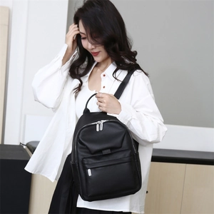 Detail of black pebbled leather backpack showing side pockets and silver zipper on model