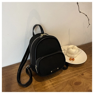 Détail d'un mini sac à dos noir avec finitions dorées sur une table en bois brun
