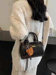 Classic black leather Boston bag with teddy bear charm shown on a casual model outfit