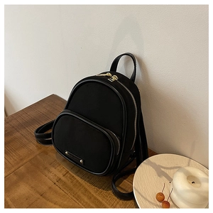 Détails d'un mini sac à dos noir avec fermetures dorées sur une table en bois