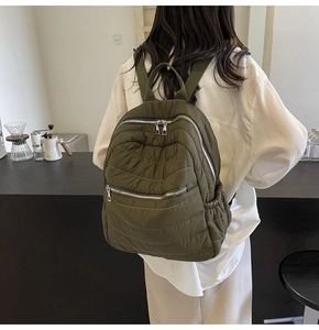Detailed side view of an olive green quilted backpack with stylish wave patterns