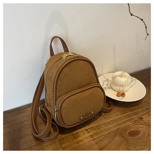 Gros plan du mini sac à dos en daim marron avec détails dorés sur table en bois