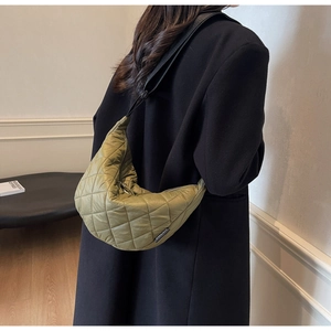 Détail du sac demi-lune en nylon matelassé vert olive avec large bandoulière sur modèle
