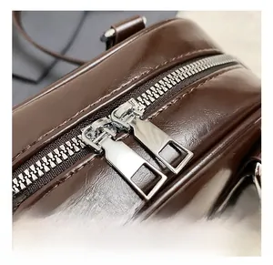 Detailed macro view of silver dual zippers on a dark brown leather textured handbag