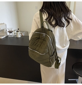 Side view of olive green quilted backpack with metallic zippers and side pockets