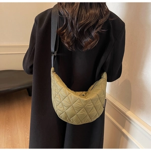 Vue détaillée du sac croissant matelassé vert herbe porté par un mannequin en manteau