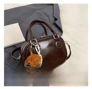 Detail of dark brown leather Boston bag with plush dog charm and silver hardware