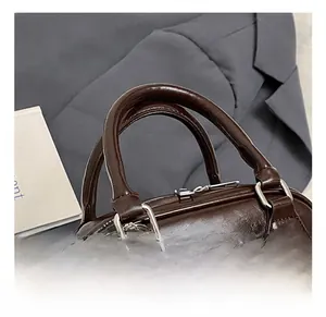 Detail showing the comfortable double handles and smooth dark brown leather texture