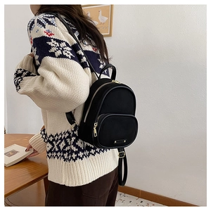 Détail d'un mini sac à dos noir avec fermetures dorées et texture de tissu raffinée