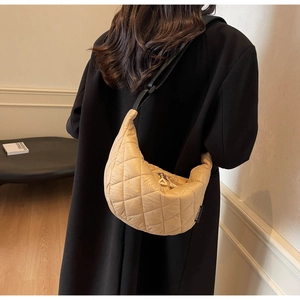 Détail du sac croissant en nylon matelassé beige avec large bandoulière noire réglable