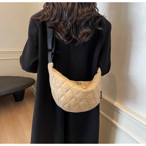 Détail du sac croissant en nylon matelassé avec bandoulière large porté par un mannequin
