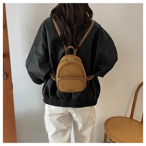 Gros plan du mini sac à dos en daim marron montrant la texture et les fermetures éclair