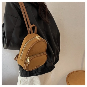 Vue détaillée du mini sac à dos marron en daim avec fermetures éclair dorées et bordures