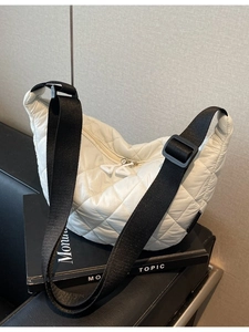 Sac demi-lune en nylon matelassé blanc avec large bandoulière noire sur fond minimaliste