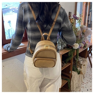 Vue détaillée du dos d'un mini sac à dos camel avec fermetures éclair dorées et sangles