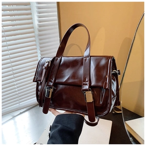 Detail of dark brown glossy leather handbag with vintage silver metal buckles and flap