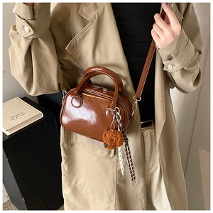 Detail of vintage brown glossy leather handbag with teddy bear charm and silk ribbon