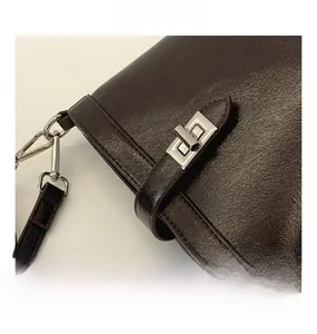 Detail of silver twist lock and leather strap hook on a dark brown bucket bag