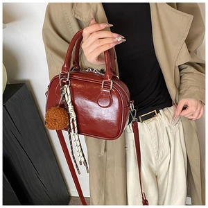Detailed shot of dark red glossy leather mini bag with bear charm and woven rope accent