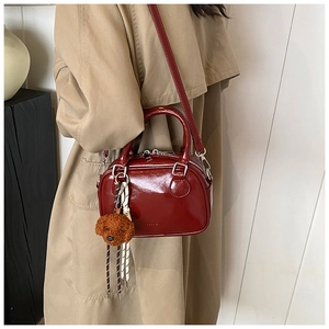 Close-up of a burgundy patent leather mini Boston bag with a cute brown teddy bear charm