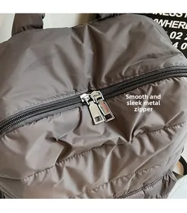 Close-up of dual silver metal zippers on grey quilted down fabric backpack