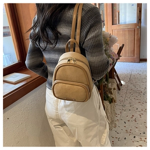 Gros plan détaillé d'un mini sac à dos kaki en daim porté par un mannequin féminin